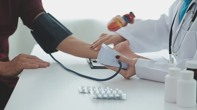 Female professional doctor examining elderly old male patient measuring high low arterial blood pressure using medical tonometer at hospital checkup appointment visit. Seniors hypertension concept.