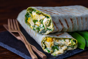 Homemade burrito wraps with boiled eggs, potato, green wild garlic and sour cream for healthy breakfast , closeup - 781502047