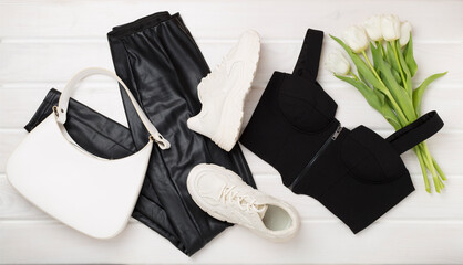 Flat lay with trendy spring outfit and flowers on wooden background