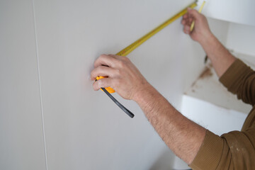 Man measuring wall with a tape measure 