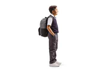 Full length profile shot of a schoolboy in a uniform standing with hands inside pockets