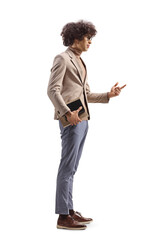 Full length profile shot of a young man holding a book and talking