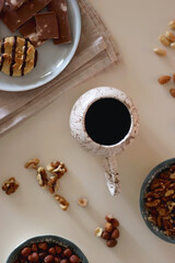 Cup of tea or coffee, cookies, macaroons, chocolate, various nuts and cocoa powder on white background. Top view.