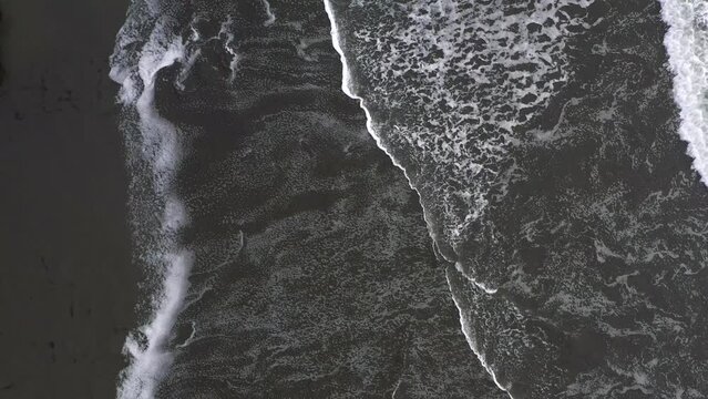 A body of water with a dark, almost black color. The water appears to be choppy, with waves crashing against the shore. Concept of power and energy