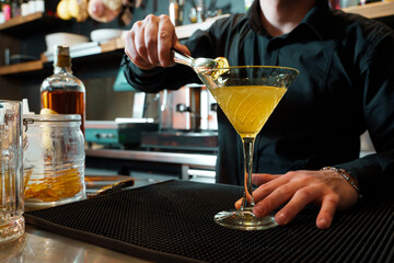 Bartender garnishing a gourmet cocktail with precision and care - luxury drink at bar counter.