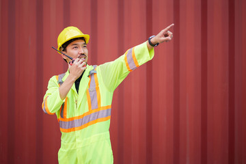 worker or engineer using walkie talkie and talking about work in containers warehouse storage