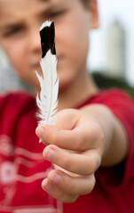 Um menino mostra em suas mãos  uma asa branca e preta