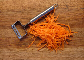 grated carrots and grater on a wooden cutting board - 781519201