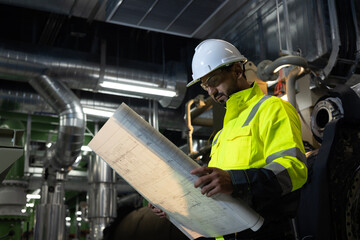 Mechanical engineer with green safety jacket hold the blue print drawing working at site line of...