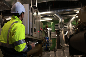 Specialist HVAC Industrial engineer with green safety jacket and PPE check piping and HVAC control...