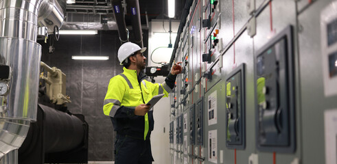Specialist HVAC Industrial engineer with green safety jacket and PPE check piping and HVAC control...