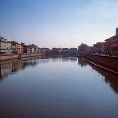 Fototapeta na wymiar The Arno river passing in the middle of Pisa, shot with analogue film
