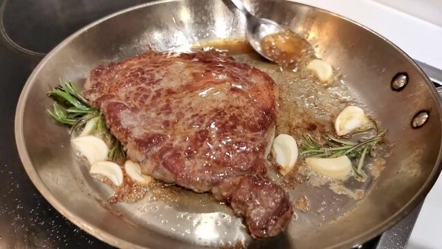 Beef steak with garlic, rosemary and butter fried in a frying pan