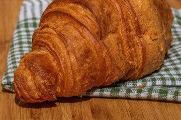 Detail of fresh croissant on wooden table. Food and breakfast concept. Close up photo of French buttery croissant