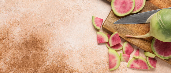 Wooden board with cut ripe watermelon radishes on grunge background