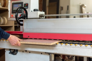 Furniture manufacturing. Gluing strips of edges on wood boards on special machine in production of cabinet furniture
