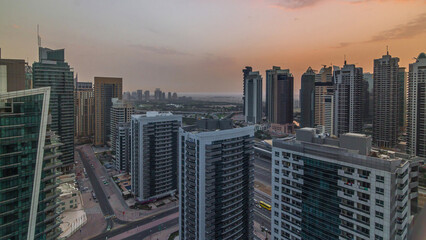 Fototapeta na wymiar Sunrise view of various skyscrapers and towers in Dubai Marina from above aerial timelapse