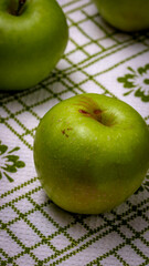  Ripe green apples on a rustic napkin on wooden table.