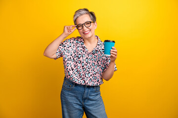 Photo portrait of lovely senior lady hold coffee paper cup drink dressed stylish leopard print garment isolated on yellow color background - 781544277