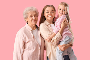 Fototapeta na wymiar Little girl with her mother and great-grandma on pink background