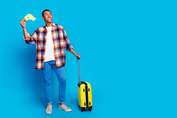 Full size photo of nice young man suitcase taxi ad empty space wear shirt isolated on blue color background