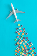 Background of round colorful cereal and plane. Colorful breakfast food. Colorful cereal loop rings, flat lay.