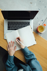 Top view, female student writes notes in blank diary notebook journal, makes goals check list,...