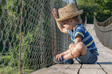 Suspension bridge. The boy sits and looks over the fence. It does not move forward (Concept: limitations in our head)