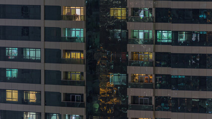 Night view of exterior apartment building timelapse. High rise skyscraper with blinking lights in...