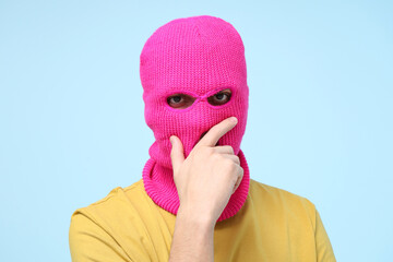 Handsome young man in balaclava on blue background