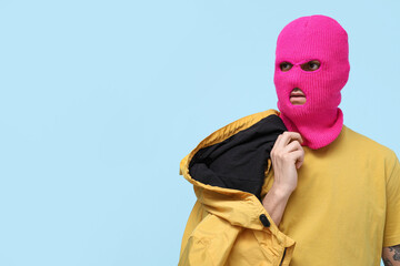 Handsome young man in balaclava with jacket on blue background