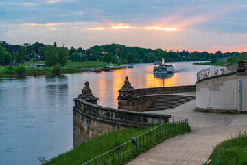 Sunset on the Elbe River in the famous city of Dresden. Tourist, pleasure boats slowly sail along the river at sunset past a beautiful staircase in the park. Concept: vacation, tourism