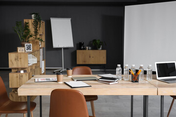 Wooden table, armchairs and stationery prepared for business meeting in modern conference hall