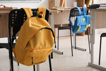 Schoolbag hanging on chair in classroom, closeup