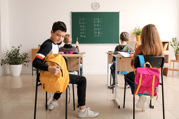 Little pupils having Math lesson at desks in classroom, back view