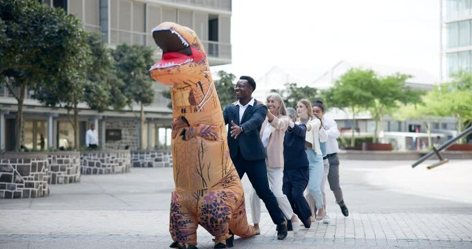 Business, people and dance outdoor in costume of inflatable dinosaur with fun and happiness at office. Funny, group and crazy team building at workplace with excited conga line with comedy character