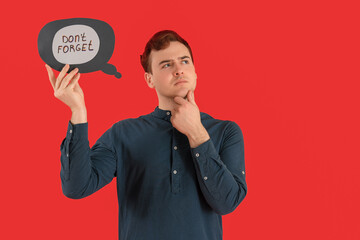 Thoughtful young man holding speech bubble with text DON'T FORGET on red background