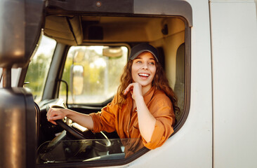 Portrait of young woman professional driver sitting and driving a big truck. Inside of vehicle....