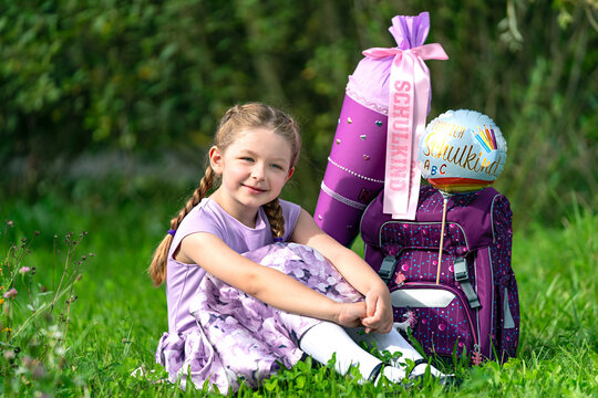 blondes gl&uuml;ckliches sechsj&auml;hriges M&auml;dchen mit Schult&uuml;te und Schulrucksack, erstkl&auml;sslerin, sonniger tag, schulanfang