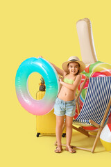 Cute little girl with inflatable ring and mattress on yellow background