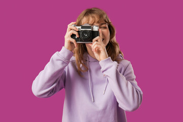 Young woman taking photo on purple background