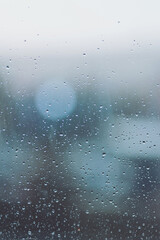 Drops of rain on glass after rain. Rain drops on window glasses surface with cloudy sunset background . Natural Pattern of raindrops isolated on cloudy background. Rainy window.
