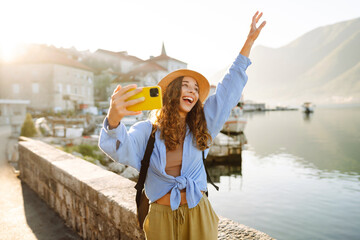 Beautiful tourist walks the streets and takes selfie using smartphone camera. Lifestyle, travel,...