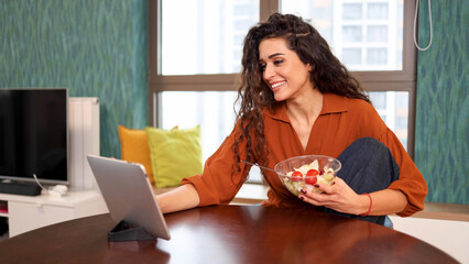 Woman eating salad and having fun online