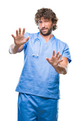 Handsome hispanic surgeon doctor man over isolated background afraid and terrified with fear expression stop gesture with hands, shouting in shock. Panic concept.