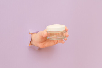 Glass cosmetic jar for face or skin cream in hand. Bottle for cosmetic beauty product, luxury makeup container, spa