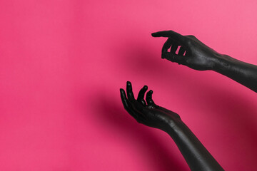 Elegant woman's hands with black paint on her skin on pink background. High Fashion art concept