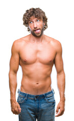 Handsome hispanic model man sexy and shirtless over isolated background sticking tongue out happy with funny expression. Emotion concept.