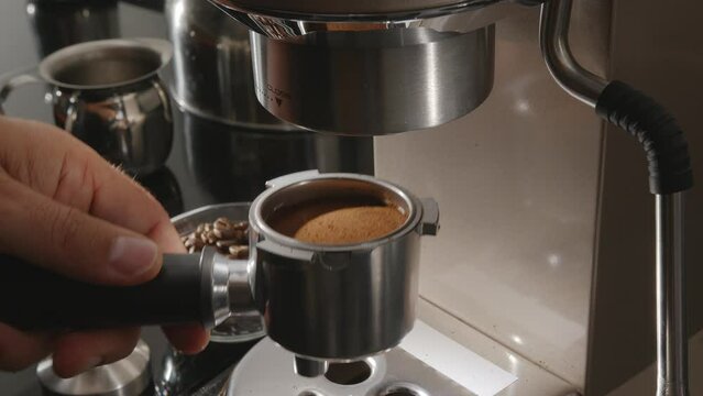 Inserting portafilter with ground coffee into the coffee machine.