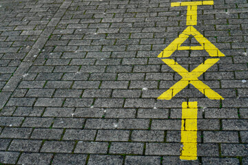 yellow taxi sign on sidewalk